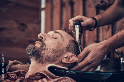 A man came to a barbershop and washes his hair. 
