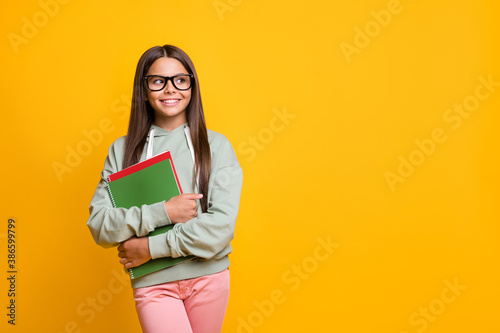 Portrait of little people smile in good mood carry copybook watch empty space isolated on vivid yellow color background