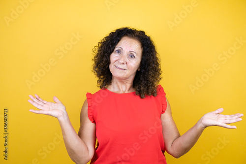 Fotografie Middle age woman wearing casual shirt standing over isolated yellow background c