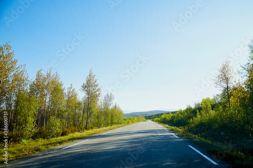 View from car windscreen with stripe relief to highway, tundra and blue sky in norht region at a sunny day