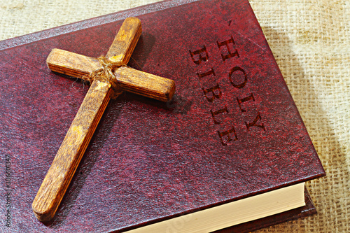 Handmade wood Christian Cross (symbol of Christianity) and vintage book Holy Bible in English. Christian religion, concept photo