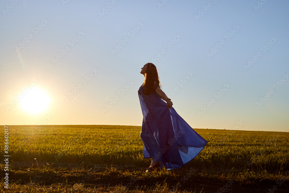 Beautiful woman or girl with magnificent figure and plastic movements walking and dancing in green field with trimmed grass in the setting sun during sunset with warm yellow light. Beautiful woman or girl with magnificent figure and plastic movements walking and dancing in green field with trimmed grass in the setting sun during sunset with warm yellow light.