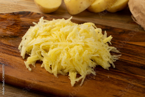 Raw Grated Potato on Wooden Cutting Board Background photo