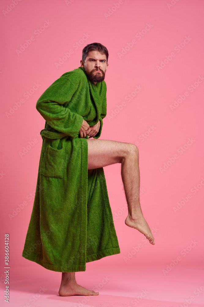 An emotional man in a green robe in full growth on a pink background gestures with his hands to the model An emotional man in a green robe in full growth on a pink background gestures with his hands to the model