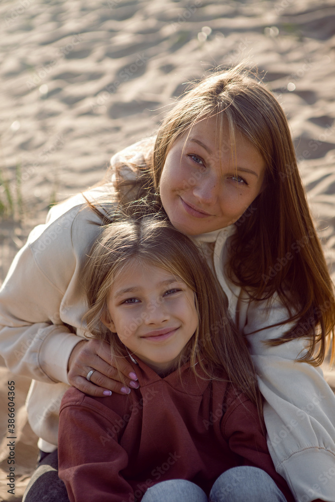 mom and daughter of a blonde in a hoodie sit mom and daughter of a blonde in a hoodie sit