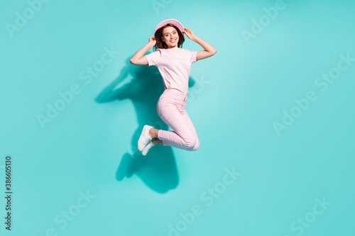 Full length body size view of her she nice attractive pretty charming cheerful teen girl jumping having fun touching hat isolated bright vivid shine vibrant green turquoise color background © deagreez