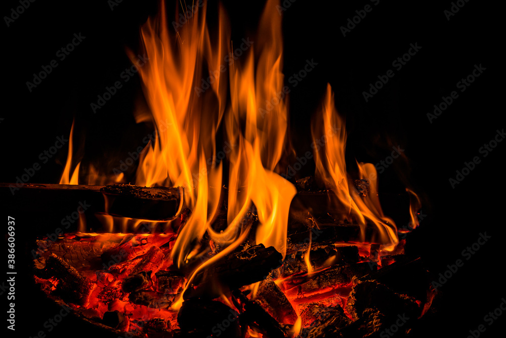 Fototapeta premium Orange flames of fireplace in dark with hot coals