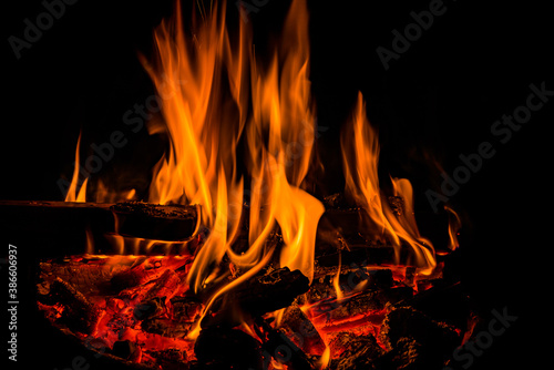 Orange flames of fireplace in dark with hot coals