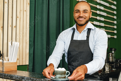 Portrait of a mixed race young man barista in coffee shop