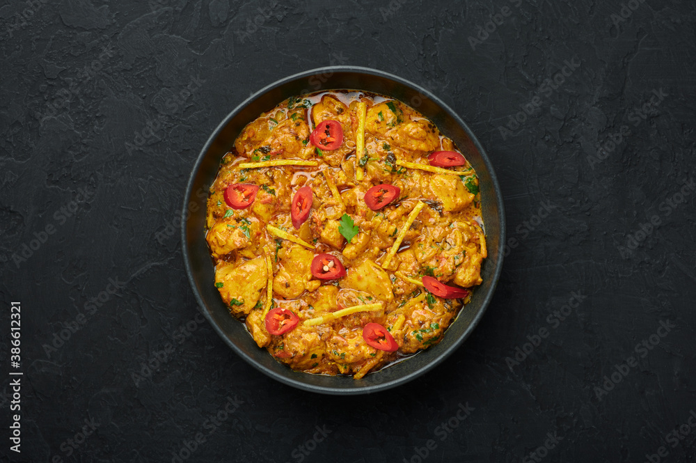 Chicken Handi in black bowl on dark slate table top. Murgh Chicken is indian cuisine curry masala dish. Asian food and meal. Top view Chicken Handi in black bowl on dark slate table top. Murgh Chicken is indian cuisine curry masala dish. Asian food and meal. Top view