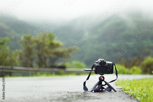 Camera lying around on the Road with lush green Mountains in the background.