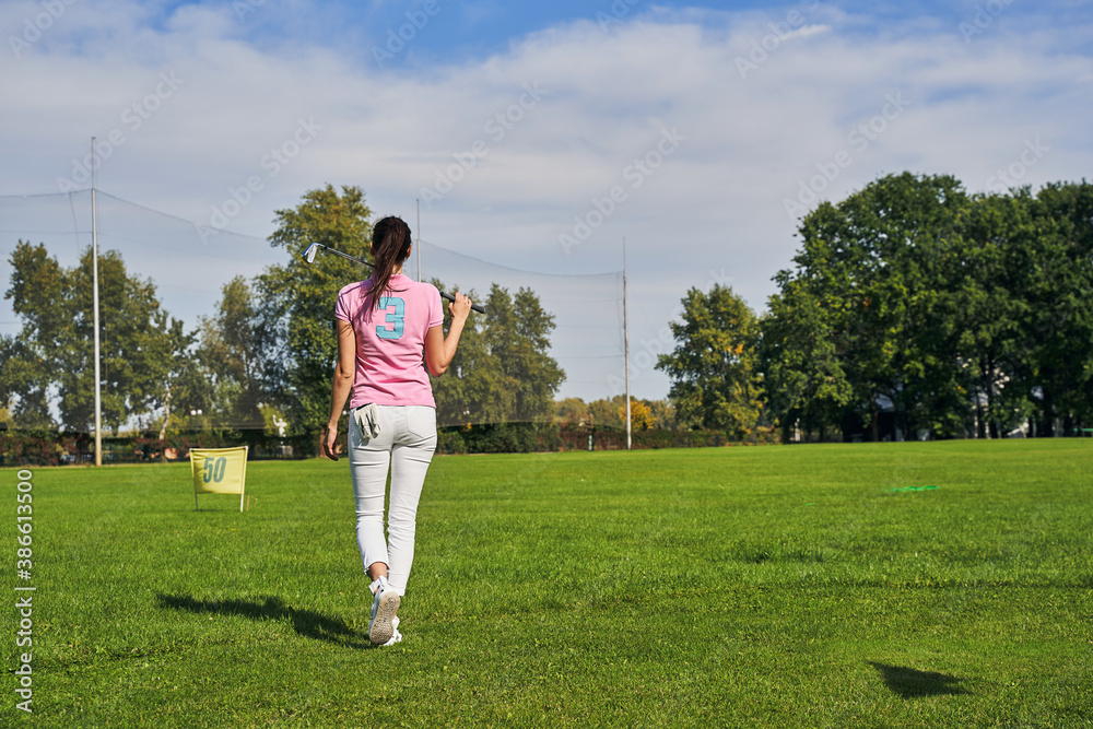 Young female player walking over the golf course
