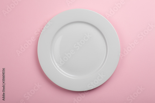 Studio photo of white empty plate on light pink background
