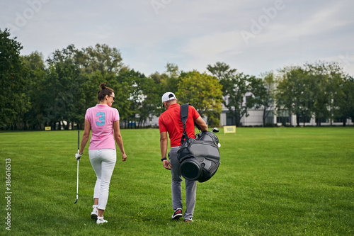 Female golfer and her trainer walking on the grass
