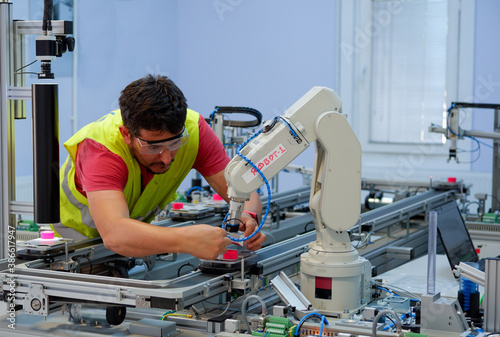 Close-up of Service Engineer ( Mechanic ) with safety glasses, repairing robot arm in a technology laboratory. Industry 4.0 concept of smart factory prototype.