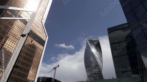 Bottom view of the glass skyscrapers of the business district against blue cloudy sky. Action. Beautiful commercial office buildings, concept of modern architecture. photo