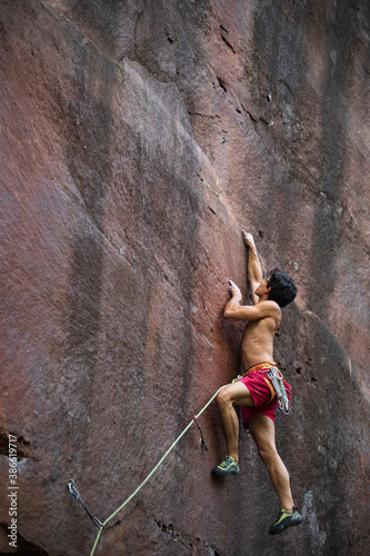 Athletic male climber advances in a climbing route on a colorful sandstone wall. photo