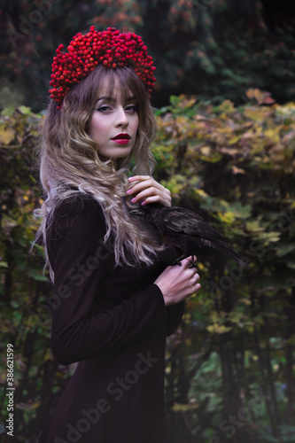 Gothic portrait of a girl in a wreath of rowan with a raven. Fall.