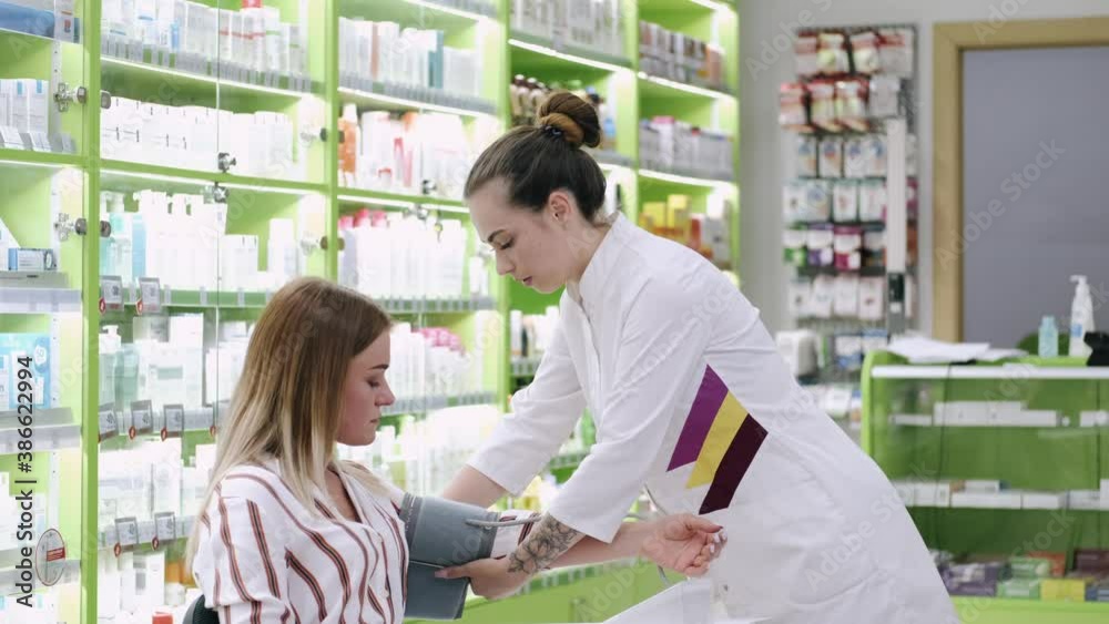 Female client is checking bloog pressure at the drugstore. The woman pharmacist is measuring blood pressure with an automatic tool. Female client is checking bloog pressure at the drugstore. The woman pharmacist is measuring blood pressure with an automatic tool.