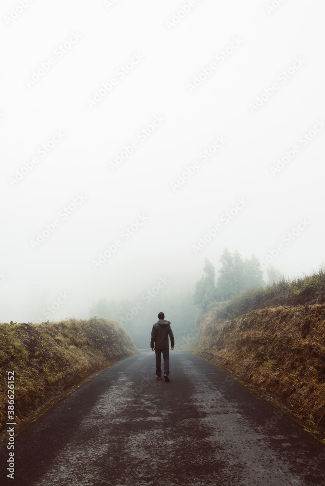 Man's silhouette walking in foggy mountains