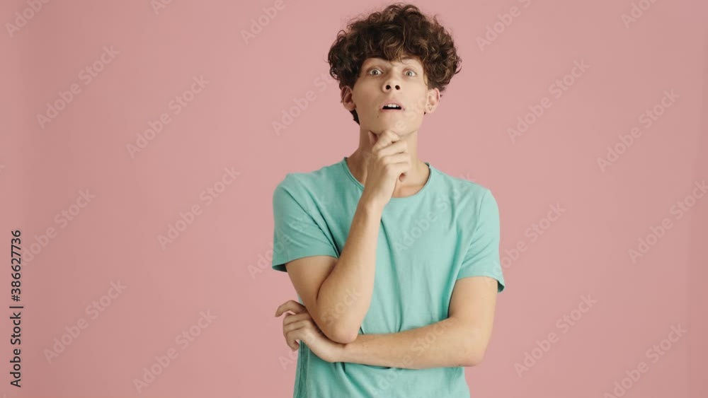 An attractive young man is nodding while looking to the camera standing isolated over pink background