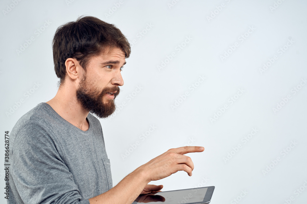 A man with a tablet in his hand internet technology communication gray jacket light background A man with a tablet in his hand internet technology communication gray jacket light background