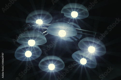 starry effects of the bulbs in a modern chandelier on the wall in the night