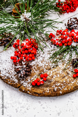 Pine bumps and branches with red rowan on an old snow-covered table