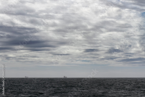 Cloudy seascape with a ships on the horizon
