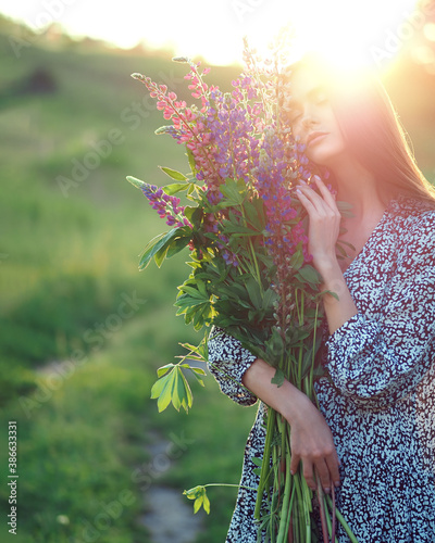Girl with lupins in a dress at sunset