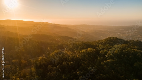 Sunset or sunrise over wild forest mountains. Aerial photo of the mountain tops with sunlight