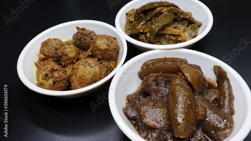 Group photograph of indian pickles or achar like amla pickle, mango pickle and lemon pickle, aavla, Aam and Nimbu ka achar sarved in white ceramic bowl, selective focus
