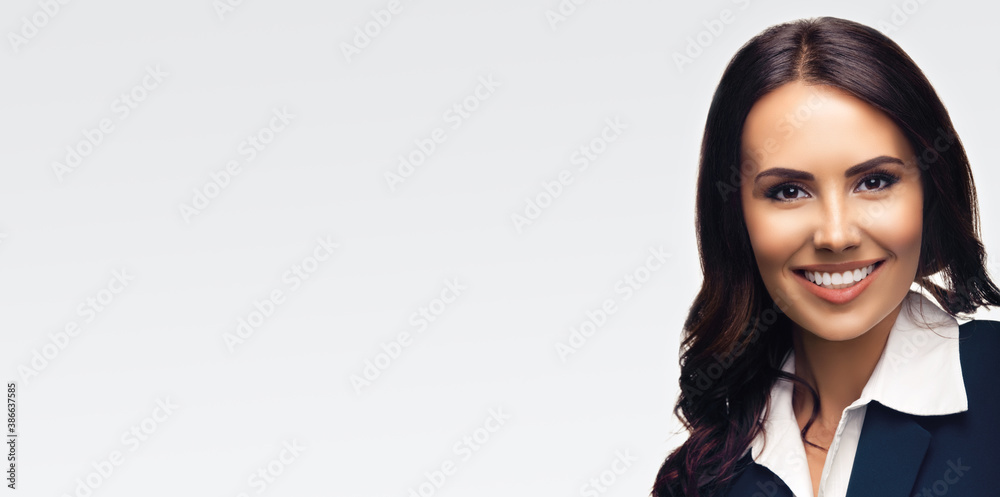 Portrait image of happy smiling beautiful young brunette businesswoman in dark blue confident suit, isolated over grey background. Copy space for some text or imaginary. Portrait image of happy smiling beautiful young brunette businesswoman in dark blue confident suit, isolated over grey background. Copy space for some text or imaginary.