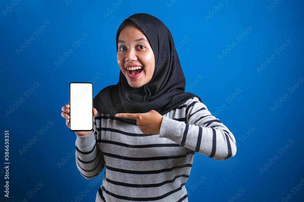 Portrait of Asian muslim woman looking at camera smiling, showing and pointing her smart phone, Portrait of Asian muslim woman looking at camera smiling, showing and pointing her smart phone,