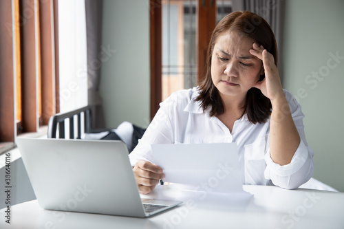 frustrated, shocked, stressed middle aged woman with expensive bill, debt invoice, eviction notice; concept of high cost of living, expensive bill, economic recession, no job no money