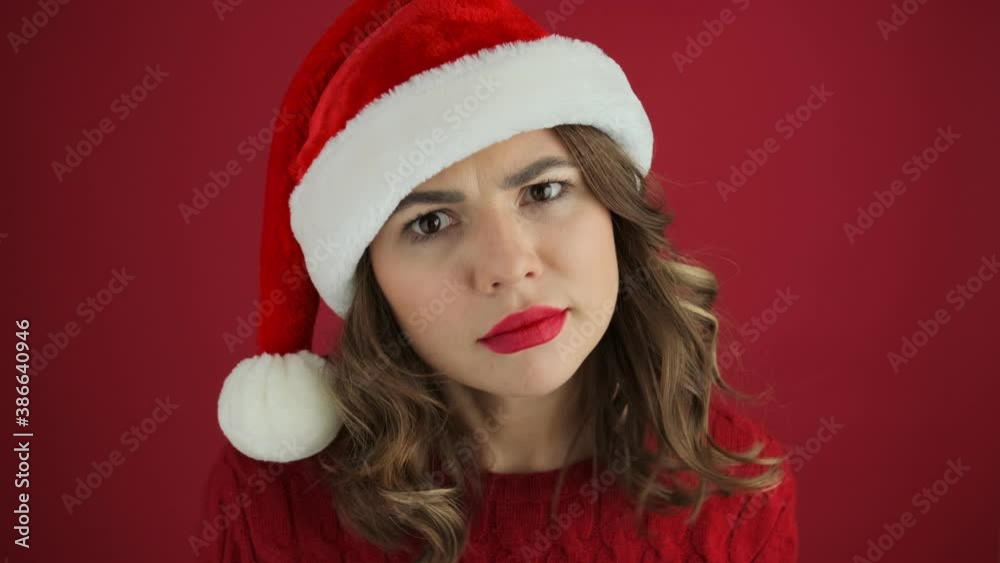 A cheerful woman wearing a warm red sweater and christmas hat is peeping for someone standing isolated over red background A cheerful woman wearing a warm red sweater and christmas hat is peeping for someone standing isolated over red background