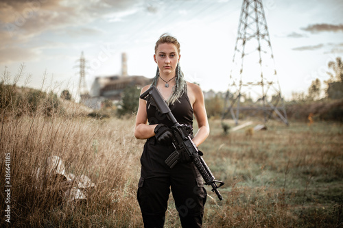 Sexy woman posing with a rifle outdoors on the background of the Chernobyl sarcophagus