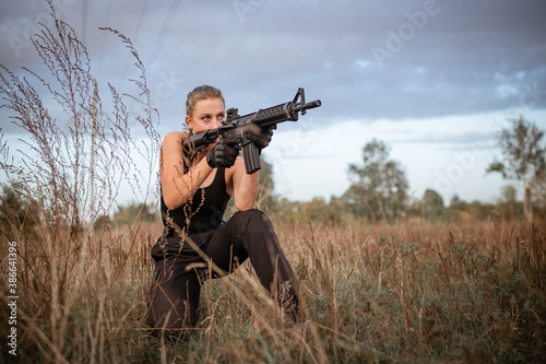 Sexy woman takes aim with rifle outdoors