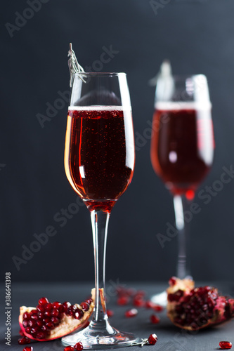 Christmas Mimosa cocktail with champagne and pomegranate on a dark table