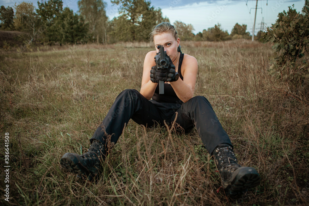 Sexy woman sitting aiming with rifle outdoors Sexy woman sitting aiming with rifle outdoors