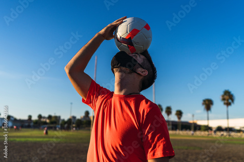 Chico joven con mascarilla por el covid 19 preparandose y jugando al futbol