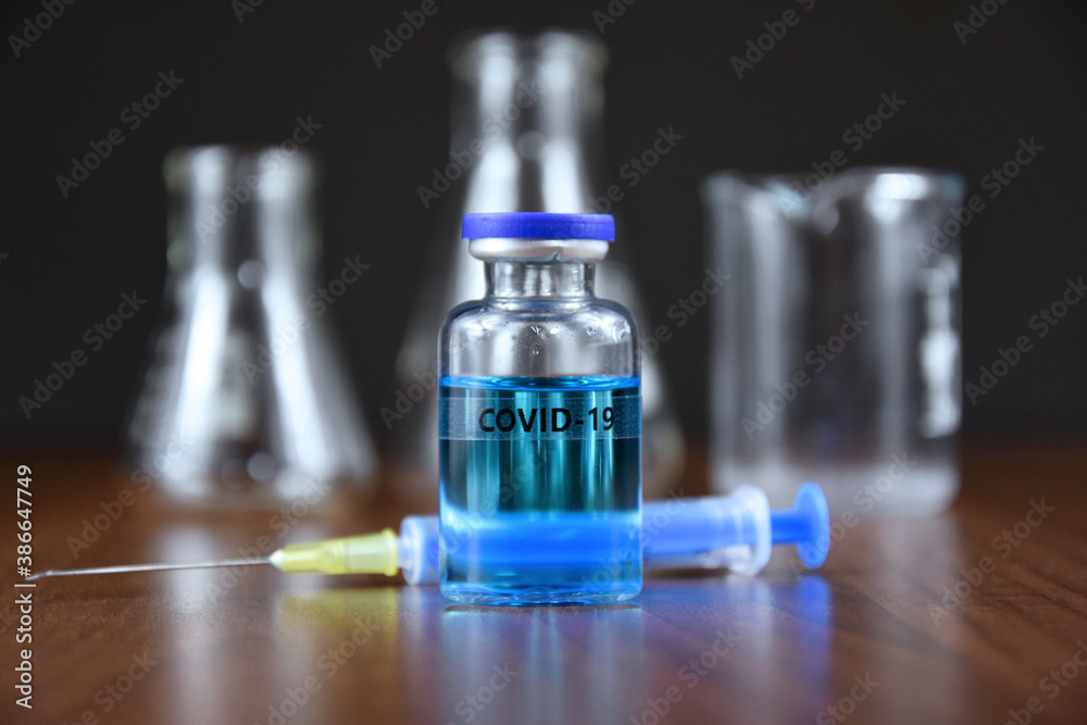 COVID-19 vaccine with syringe stock images. Coronavirus vaccine and injection on a laboratory background images. Glass laboratory equipment. Laboratory accessories stock photo