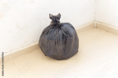 a full black trash bag on the floor to throw away photo