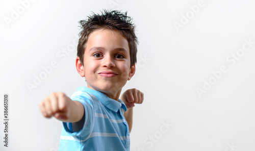 A boy in a blue T-shirt shows his fist to the camera. Focus on the face.