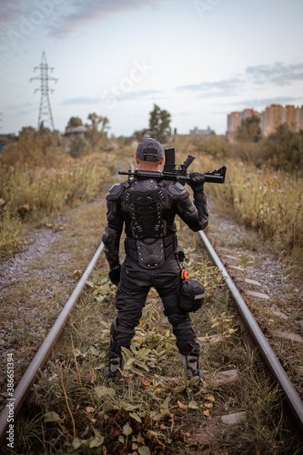 a man with a rifle in uniform stands with his back