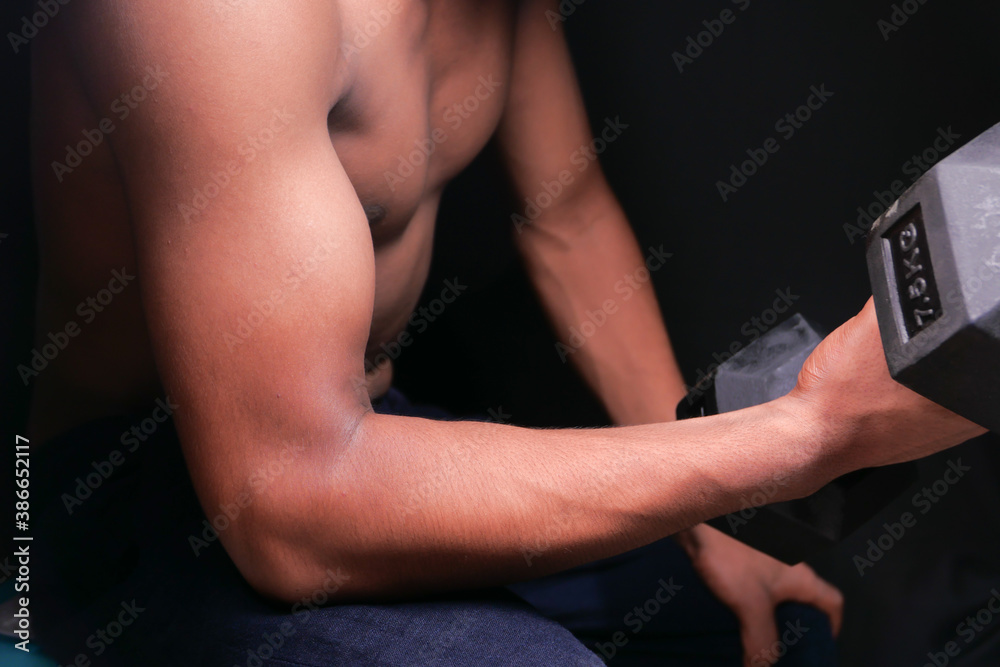 Naklejka premium young man hand exercising with dumbbells indoor.