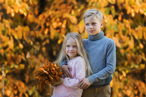 Happy children outdoors. Two kids having fun in autumn park. Cute little brother and sister on a walk in autumn day. Family, fashion, vacation and lifestyle concept.