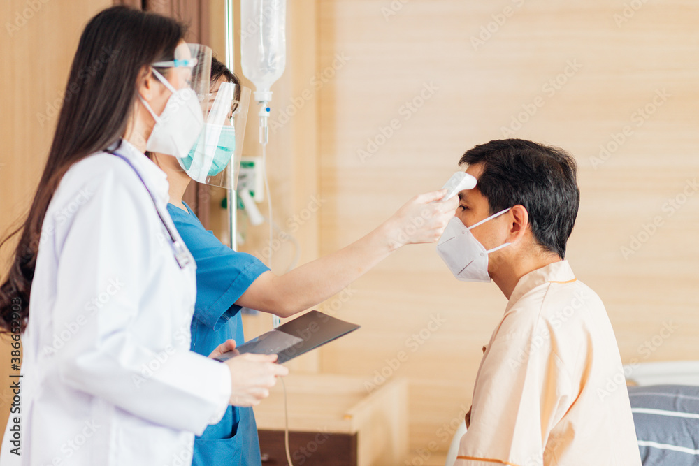 Asian female doctor and nurse wearing mask checking health of senior old patient in hospital recovery room. Woman medic checking heart rate pulse and giving health care advisory.