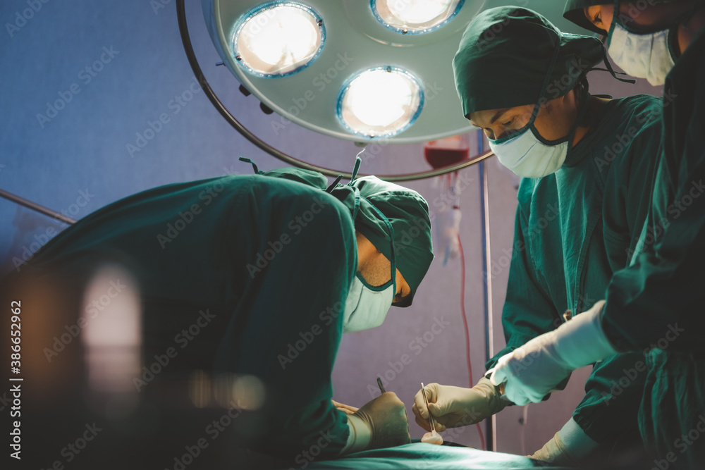 Professional medical team performing surgical operation in operating room hospital. Surgeons doctor work during operation on intensive care patient in hospital.