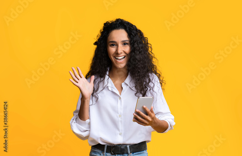 Excited Happy Young Woman With Smartphone In Hands Standing Over Yellow Background
